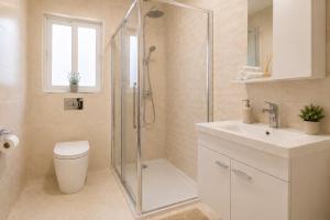 a bathroom with a shower and a toilet and a sink at Three Bedroom Qormi Home in Santa Venera +8 photos