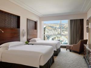 a hotel room with three beds and a large window at Makkah Clock Royal Tower, A Fairmont Hotel in Mecca +280 photos