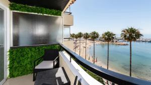 a balcony with a view of the ocean and palm trees at Marbella Beachfront Studio with Stunning Sea Views in Marbella