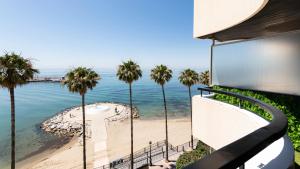 a view of the beach from a balcony with palm trees at Marbella Beachfront Studio with Stunning Sea Views in Marbella