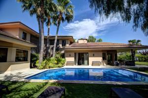 a swimming pool in front of a house with palm trees at Villa Terramar by Hello Homes Sitges in Sitges