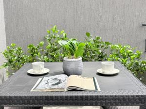 a table with a book and two cups and a vase at Exclusivo Apartamento Céntrico con Terraza Privada in Sogamoso +3 photos