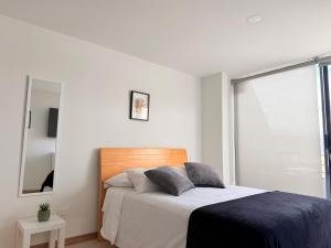 a white bedroom with a bed and a mirror at Exclusivo Apartamento Céntrico con Terraza Privada in Sogamoso
