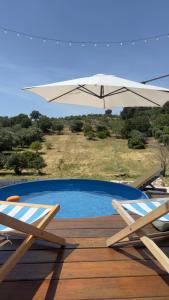 a swimming pool with two chairs and an umbrella at La Mia Lamia in Cisternino