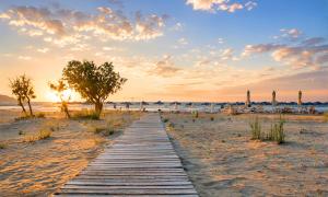 a wooden pathway on the beach at sunset at Georgioupolis Blue Villa in Georgioupolis