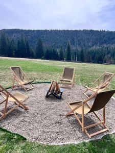 three chairs and a wooden table in a field at Лайт Хайс Буковель in Palyanytsya