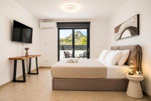 a bedroom with a large bed and a television at AVENTINE - Luxury Residences with Private Pools in Kalithies