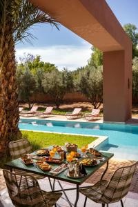 a table with food on it next to a swimming pool at Palais Zaitunay in Marrakesh