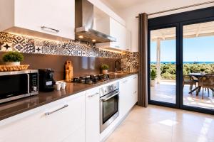 a kitchen with white cabinets and a view of the ocean at AVENTINE - Luxury Residences with Private Pools in Kalithies