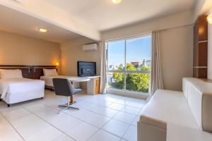a hotel room with two beds and a desk and a window at Tri Hotel Executive Santa Maria in Santa Maria