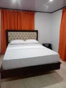 a bedroom with a large white bed with an orange curtain at Finca la santa in San Luis de Cubarral