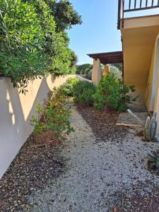 a gravel path next to a house with a fence at Casa Logos Stintino - Private pool in Stintino