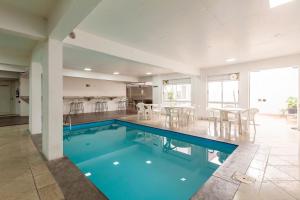 a swimming pool in a living room with a table and chairs at Tri Hotel Executive Santa Maria in Santa Maria