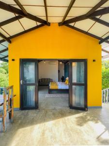 a room with a yellow wall and a bed at Turtle Breeze Rekawa in Tangalle