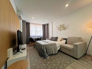 a bedroom with a bed and a couch and a television at Timeless Beach V - Apartment in Armação de Pêra