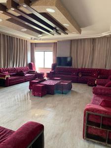 a living room with red couches and a tv at جبال جرش in Jerash