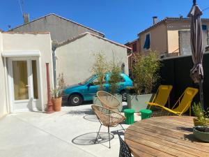 a patio with a table and chairs and a blue car at Maison entière cosy calme parking animaux ok in Carcassonne