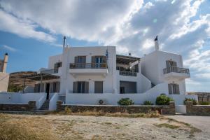 a white house on the beach with a cloudy sky at Easy Living Tinos in Vrachonisída Chántra