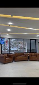 a row of brown couches in a room with windows at Seven sky hotel in Murree