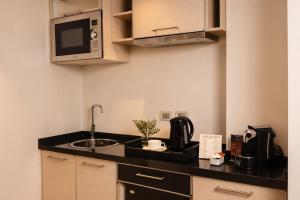 a small kitchen with a sink and a microwave at Hotel Sommelier Agustinas in Santiago +17 photos