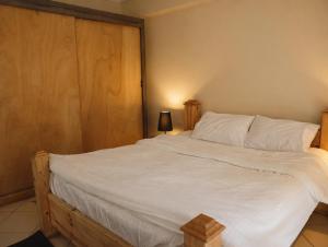 a bedroom with a large white bed with a wooden headboard at Casa Dòdò - Sunny Lakes Compound in Sharm El Sheikh +8 photos