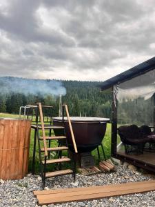 a bath tub sitting on a grill next to a house at Лайт Хайс Буковель in Palyanytsya +6 photos