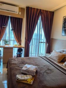 a bedroom with a large bed with two towels on it at Studio Pleasant Tifolia in Jakarta +32 photos