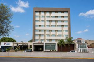 a tall white building with cars parked in front of it at Hotel Guadalajara Plaza Ejecutivo in Guadalajara