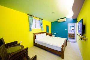 a yellow and blue bedroom with a bed and a television at Baisha 31 B&B in Hengchun South Gate