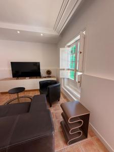 a living room with a black couch and a television at Oasis de César- Arquitectura Manriqueña in Costa Teguise