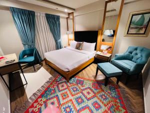 a bedroom with a bed and two chairs and a mirror at Lahore Continental Hotel in Lahore