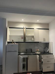 a kitchen with white cabinets and a white refrigerator at Vokopola Villa in Sarandë +10 photos