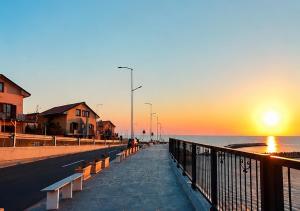 a pier with benches and the ocean at sunset at Reyna Breeze Apartment in Constanţa