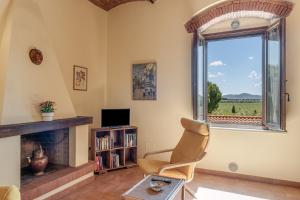 a living room with a fireplace and a chair and a window at Agriturismo Il Pescinone in Venturina Terme