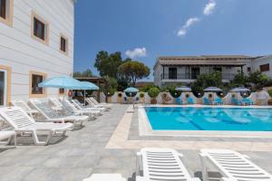 a pool with chairs and umbrellas next to a building at on the STRIP-Studio 1 in Kavos