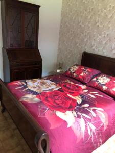 a bed with red sheets with roses on it at Gîte Le Colombet in Audrix +6 photos