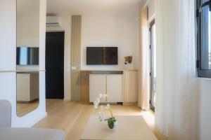 a living room with a tv and a vase with flowers at Hotel by Jon in Dhërmi