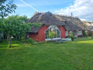 a red house with a thatched roof and a yard at Ferienhaus Sommer in Nordborg