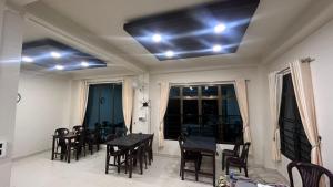 a dining room with a table and chairs and lights on the ceiling at Seven Miles Hotel in Āīzawl