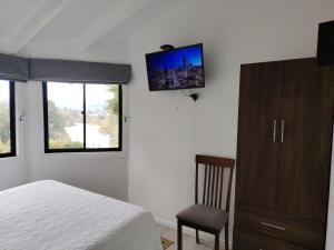 a bedroom with a bed and a tv on the wall at Cabañas Vistas al Río Villarrica in Villarrica