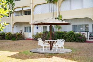 a table with chairs and an umbrella in front of a building at Golden View Unit 204 in Saint James