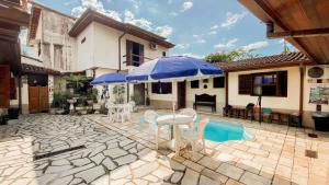 a patio with two blue umbrellas and a table and chairs at Pousada Mercador in Paraty