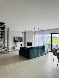 a living room with a green couch and a staircase at Pod Skrzydłami II in Liksajny