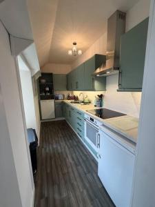 a kitchen with green cabinets and a wooden floor at Snowdrop Cottage in Orkney