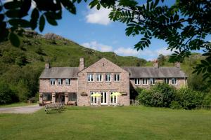 uma grande casa de pedra com uma colina ao fundo em YHA Eskdale em Eskdale