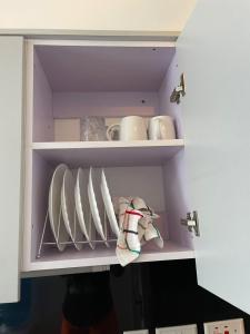 a cupboard with plates and mugs in it at Naivasha road Studio Opposite ILRI in Nairobi