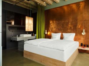 a bedroom with a large white bed and a sink at 25hours Hotel Bikini Berlin in Berlin