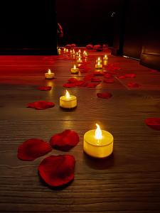 a group of candles on a wooden floor with red flowers at 007 Loveroom Secrète Jacuzzi privé Cinéma 4K in Courcouronnes