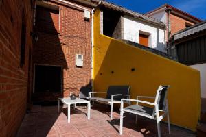 eine Terrasse mit Stühlen und einem Tisch und einer gelben Wand in der Unterkunft Sol River in Guardo