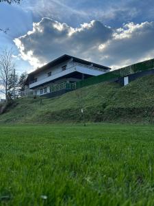a building on top of a hill with a green field at Villa Imperium Indoor & Outdoor Pool Riverfront Bjelašnica View in SJJ